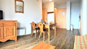 Una habitación con una mesa de comedor de madera, sillas, un armario de madera y un espejo en la pared.