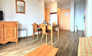 A room with a wooden dining table, chairs, a wooden cabinet, and a mirror on the wall.