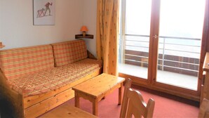 Una habitación con sofá, una mesita, lámpara y ventana con vistas.