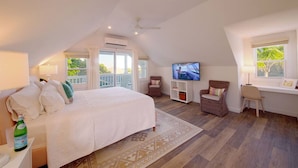 A spacious bedroom with a large bed, a TV, and a balcony. - Charming 2BR Island Cottage with Pool & Generator (Governor`s Harbour)