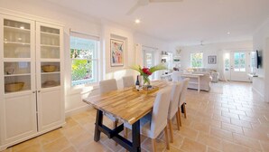 A spacious kitchen with a wooden table, white cabinets, and a dining area with chairs. - Charming 2BR Island Cottage with Pool & Generator (Governor`s Harbour)