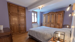 A bedroom with a large bed, wooden wardrobe, and a small bedside table. - Le Pétillant - LE BREUIL (LE BREUIL)