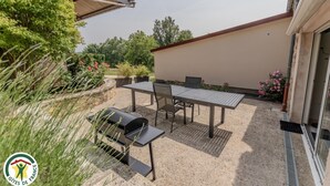 An outdoor patio with a table and chairs, a grill, and potted plants. - Le Pétillant - LE BREUIL (LE BREUIL)