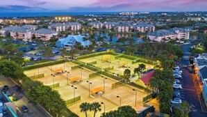 Vista aérea de un complejo turístico con varias edificaciones, una cancha deportiva y vegetación circundante.