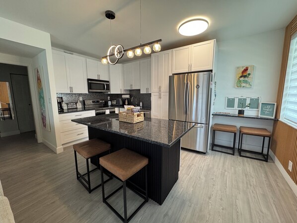 A modern kitchen with a central island, stainless steel appliances, and a pendant light fixture.