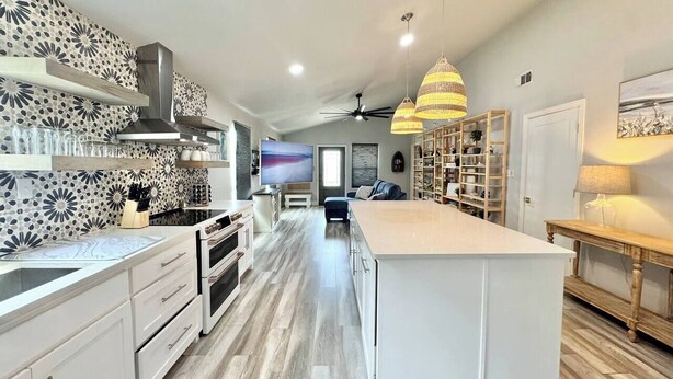 Een moderne keuken met witte kasten, een groot eiland en een patroon backsplash.