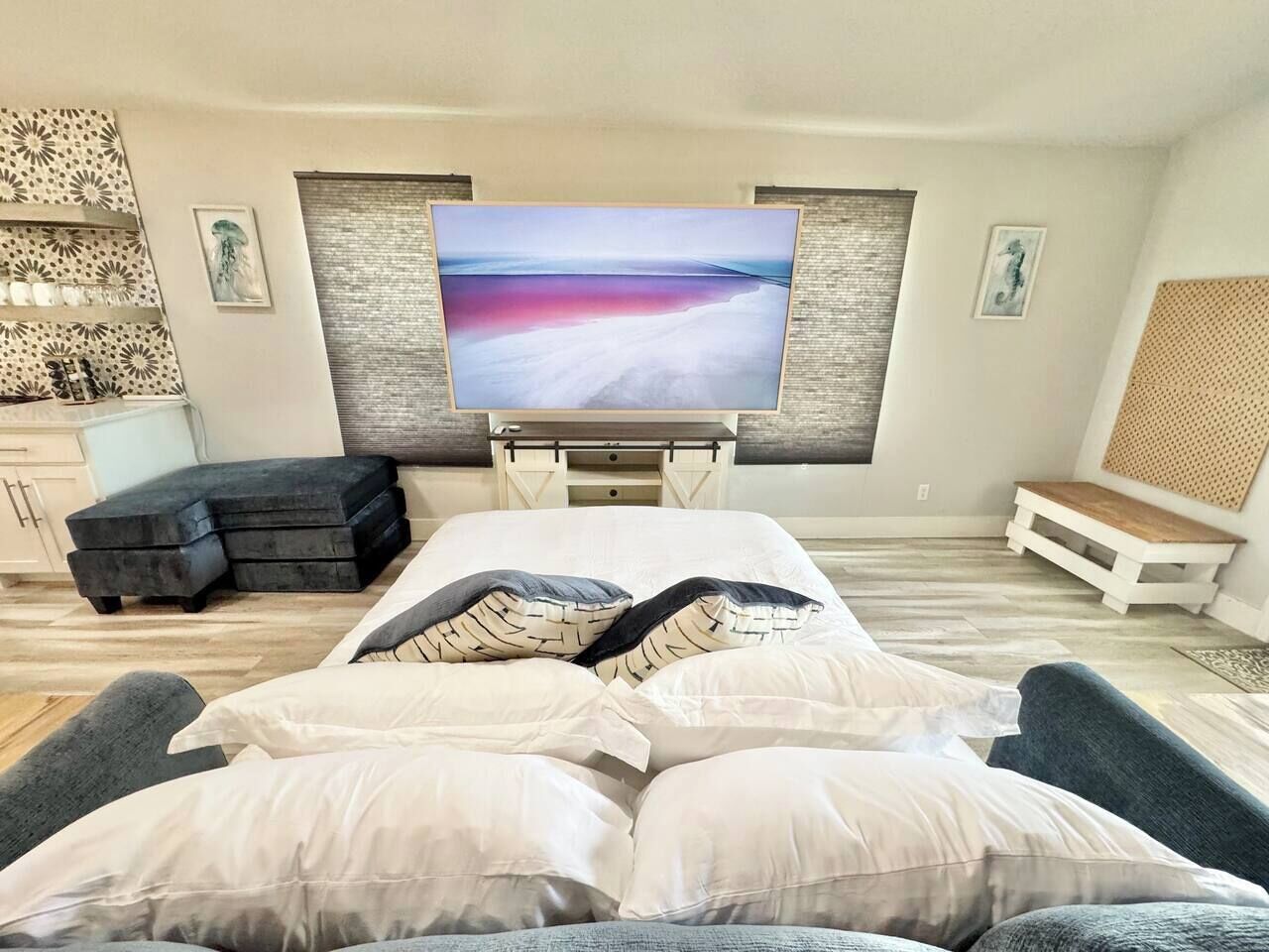Une chambre moderne avec un lit, une télévision, un banc et un mur décoré d’œuvres d’art.