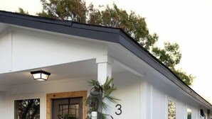 Een wit huis met een veranda, een bank en een krans bij de deur.