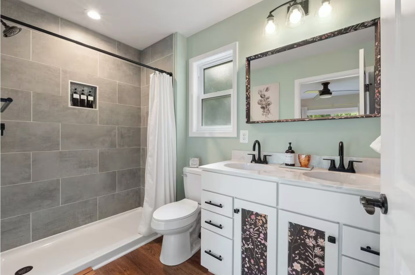 A bathroom with a shower, toilet, and vanity with a mirror.