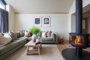 A modern living room with a sectional sofa, a coffee table, a fireplace, and two framed botanical prints on the wall.