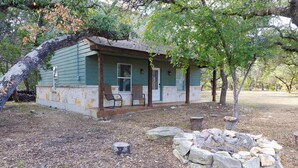 Un chalet rustique doté d’une véranda, de murs en pierre et d’un foyer extérieur.