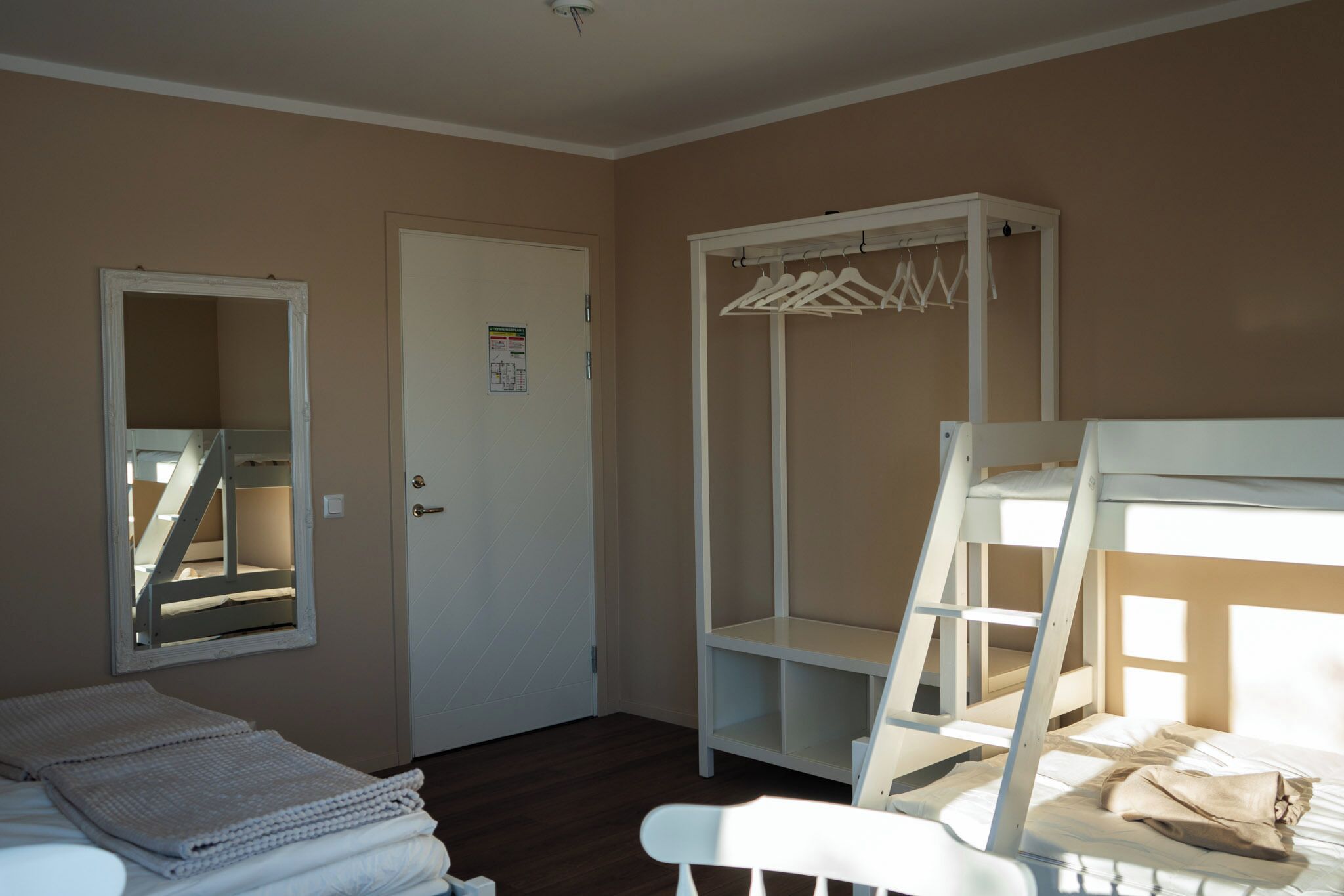 Un dormitorio con literas, un armario, un espejo y una puerta.