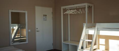 Un dormitorio con literas, un armario, un espejo y una puerta.