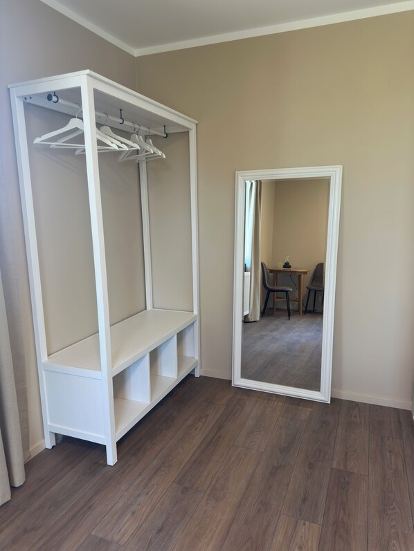 Une pièce avec une armoire blanche, un miroir et, au fond, un coin repas.