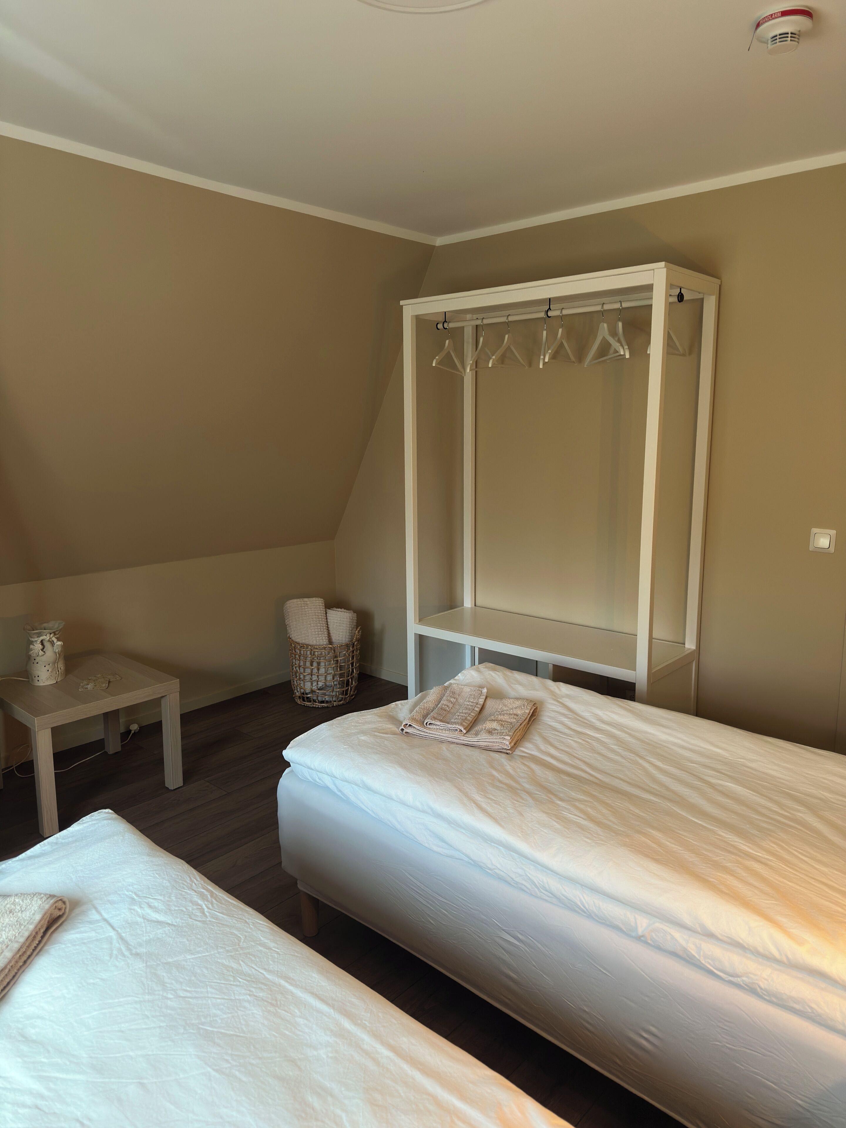 Ein Schlafzimmer mit zwei Betten, einem Nachttisch, einem Kleiderschrank und einem kleinen Korb.