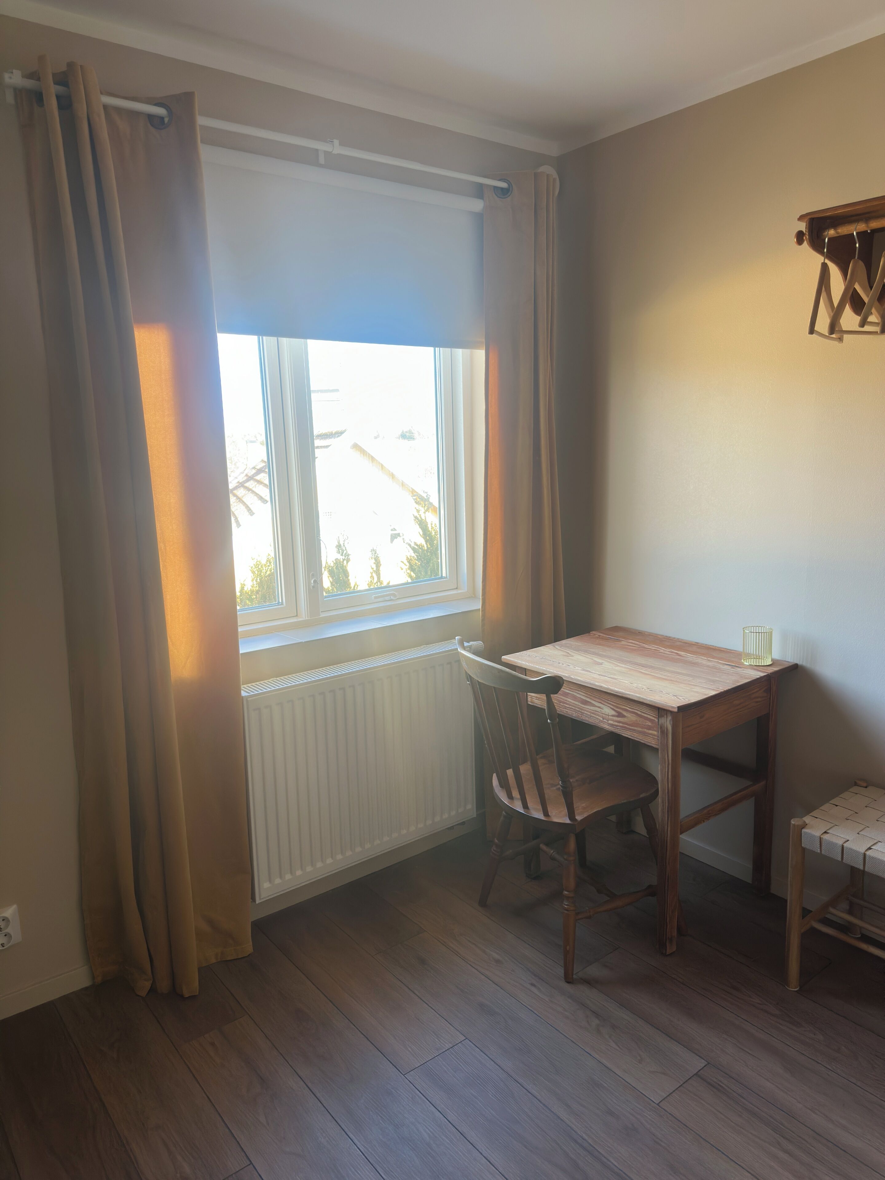 A room with a window, a table, a chair, and a radiator.