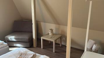 Een slaapkamer met een bed, een stoel, een klein tafeltje en een hangende lamp.