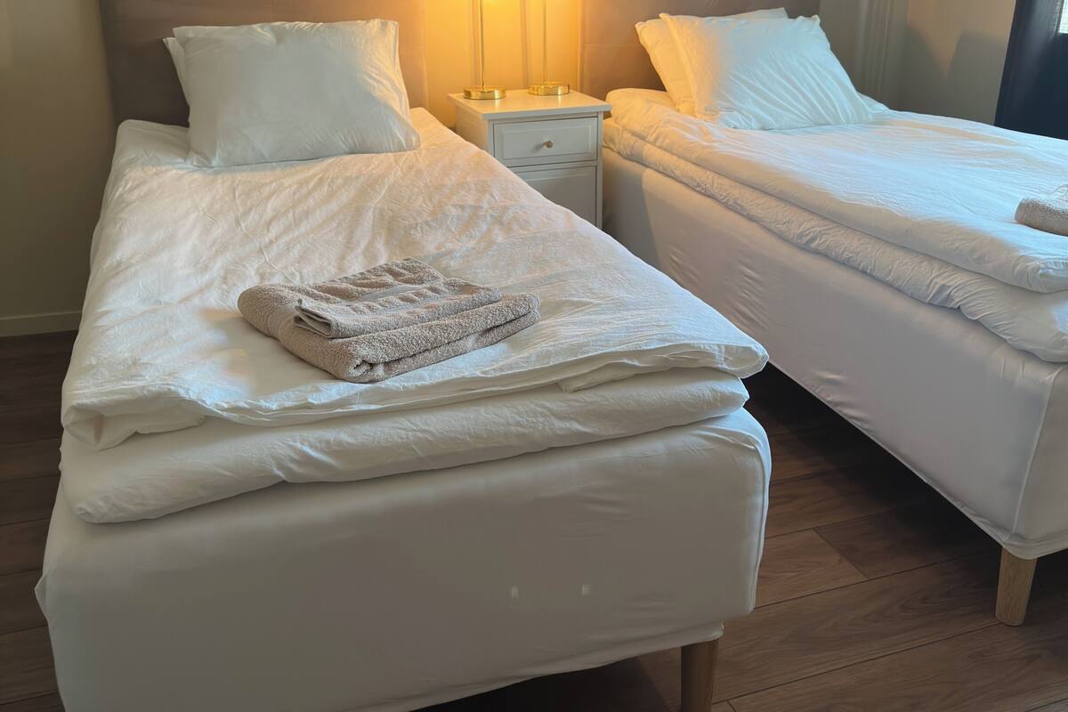 A hotel room with two beds, a nightstand, and bedside lamps.