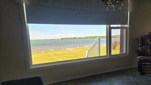 Una habitación con un ventanal grande que da a un campo de césped y una masa de agua.