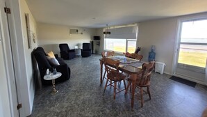 Amplia sala de estar con una mesa de comedor, asientos cómodos, un ventanal con vistas y un dispensador de agua.
