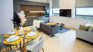 A modern living space with a dining area, a sofa, and a television.