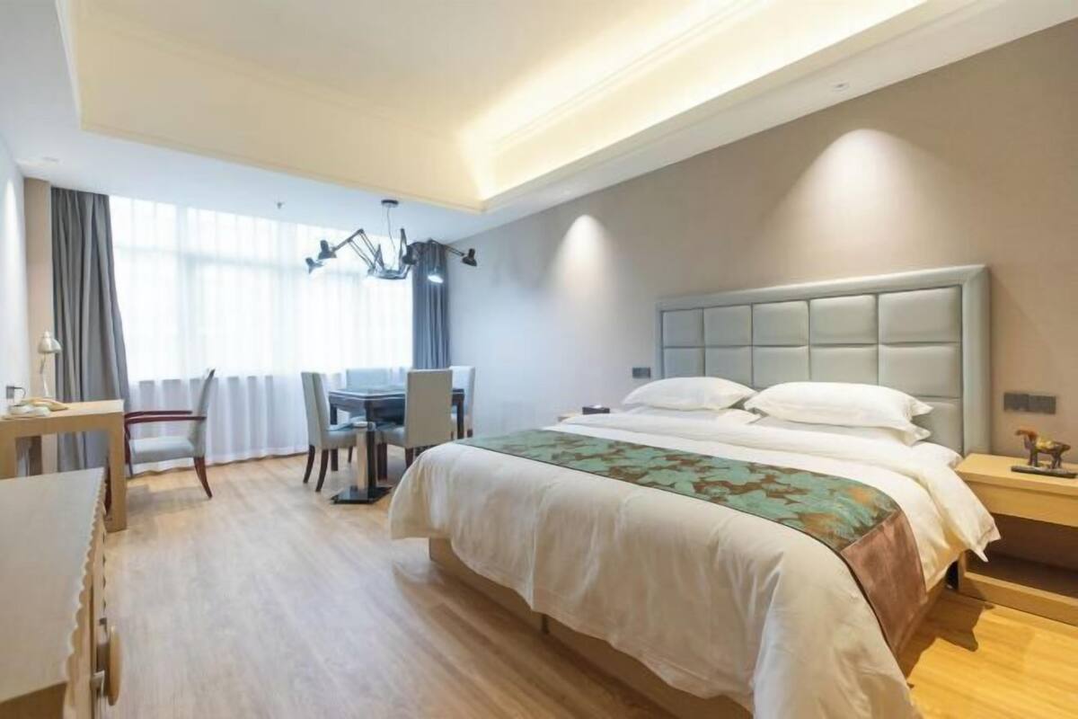 A hotel room with a large bed, a desk, and a chair.