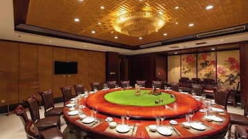 A conference room with a round table, chairs, and a television screen.