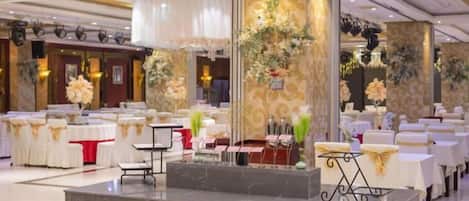 Un salón de banquetes con mesas redondas, una recepción central y decoración floral.