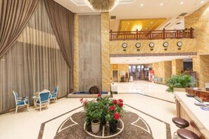 Un hall de hotel con mostrador de recepción, zona de estar y un centro de mesa decorativo.
