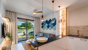 A modern kitchen with a central island, a dining area with a view of a pool, and a living room with a large window.