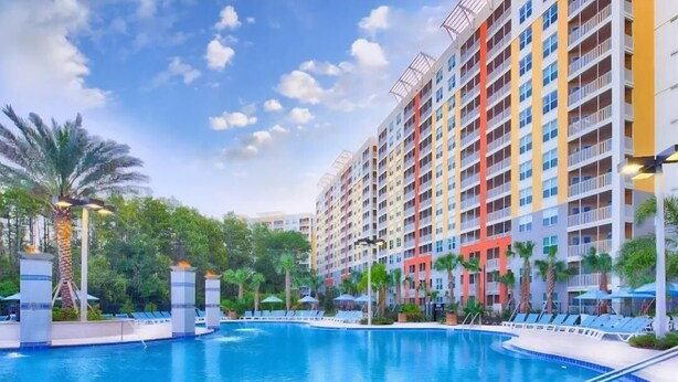 A swimming pool with lounge chairs, surrounded by multi-story buildings with balconies. - July 4 week '25 close to Disney Kissimmee / Orlando (Kissimmee)