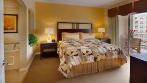 A hotel room with a large bed, two bedside tables with lamps, a potted plant, and a view of a balcony. - July 4 week '25 close to Disney Kissimmee / Orlando (Kissimmee)