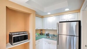 A compact kitchen with white cabinets, a stainless steel refrigerator, a microwave, and a coffee maker. - July 4 week '25 close to Disney Kissimmee / Orlando (Kissimmee)