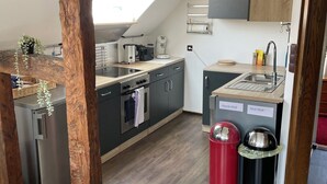 A compact kitchen with modern appliances, wooden beams, and a skylight. - Feel good and relax in an old farmhouse (Wiehl)
