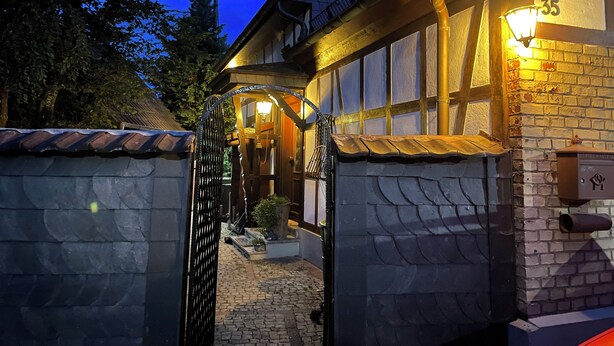 A traditional building with a stone facade, a wooden entrance gate, and a lit window sign indicating the number 35. - Feel good and relax in an old farmhouse (Wiehl)