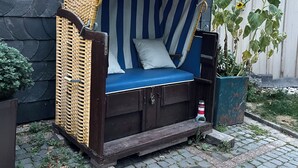 A small outdoor seating area with a wicker chair and a blue and white striped cushion. - Feel good and relax in an old farmhouse (Wiehl)