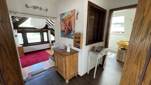 A room with a wooden cabinet, a painting, a window with blinds, a radiator, and a red carpet. - Feel good and relax in an old farmhouse (Wiehl)