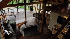 Een ruime woonkamer met een houten terras, een keuken met een bar en een grote bank.