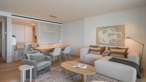 A modern living room with a sofa, chairs, a coffee table, and a dining area with a table and chairs. - Savoy Monumentalis IV – Luxury and Unmatched Views (Funchal)
