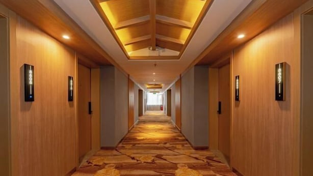 A long, narrow hotel corridor with wooden paneling, a patterned carpet, and illuminated wall sconces. - Yibin Grand Hotel (Yibin)