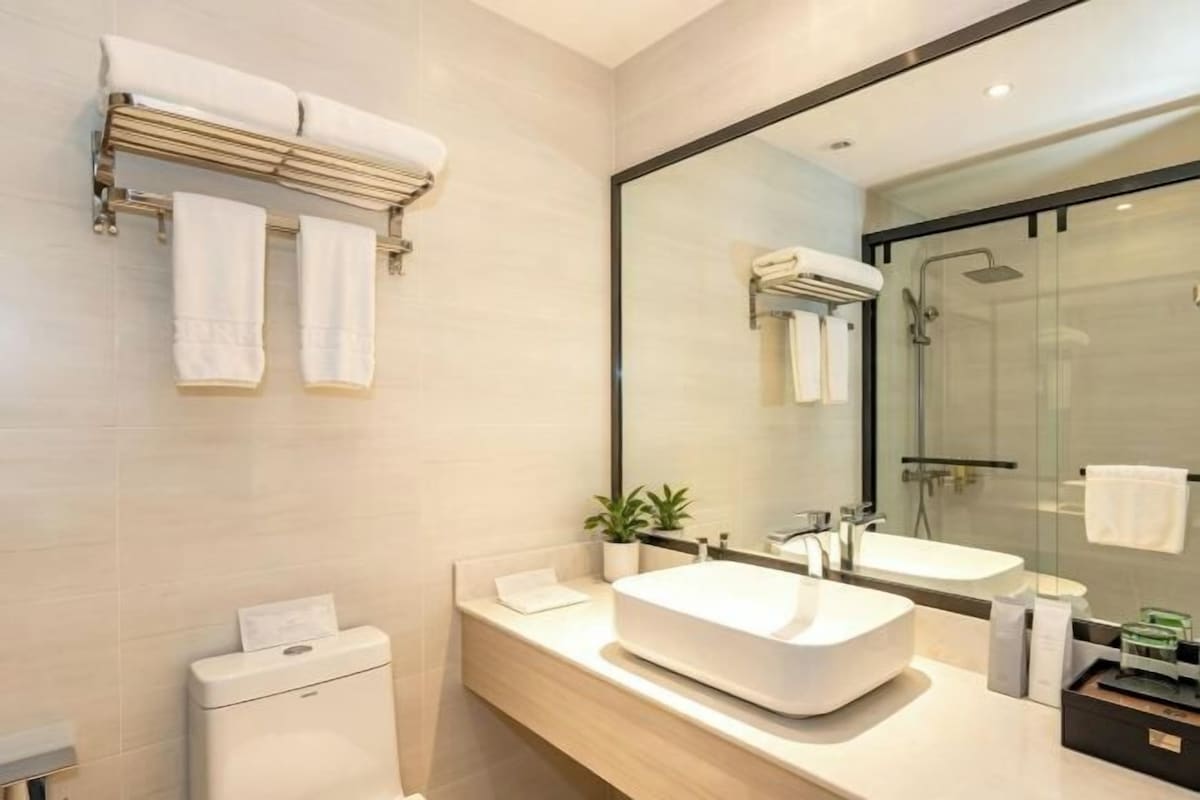 Un baño moderno con un espejo grande, dos lavamanos, un inodoro y una cabina de ducha de vidrio.