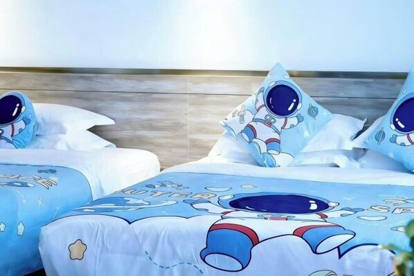Habitación de hotel con dos camas, cada una con ropa y almohadas con temática de astronautas.