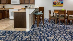 A kitchen with dark wooden cabinets, a white microwave, and a white stove. There is a blue patterned carpet on the floor. - Charming 2-bedroom resort in lovely Midway with gym, indoor pool and more. (Midway)