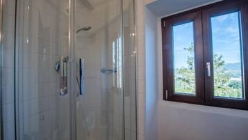 Eine gläserne Dusche mit Blick auf eine Landschaft durch ein Fenster.