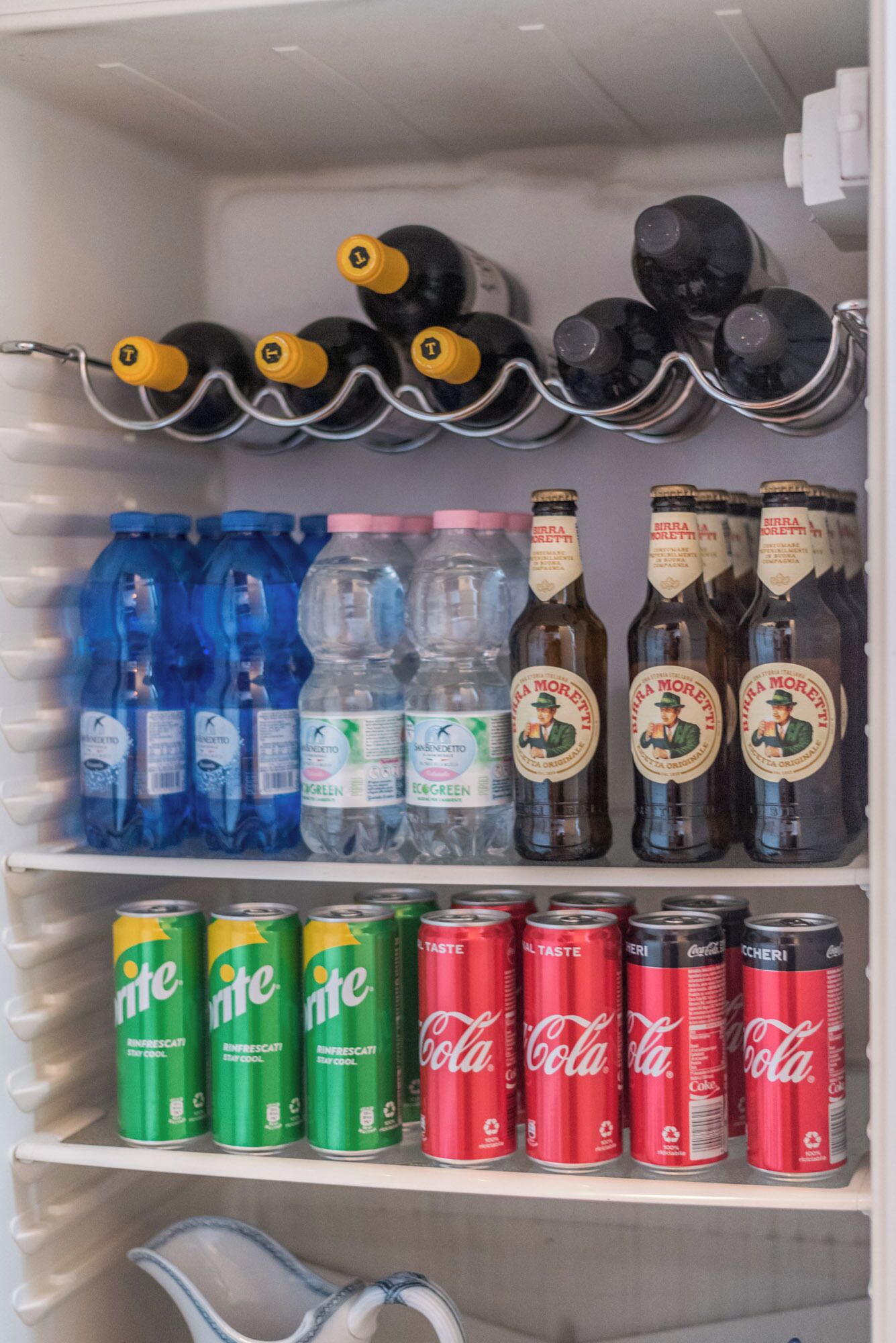 Ein Kühlschrank gefüllt mit verschiedenen Getränken, darunter Flaschenwasser, Bier und Limonade.