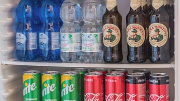 Ein Kühlschrank gefüllt mit verschiedenen Getränken, darunter Flaschenwasser, Bier und Limonade.