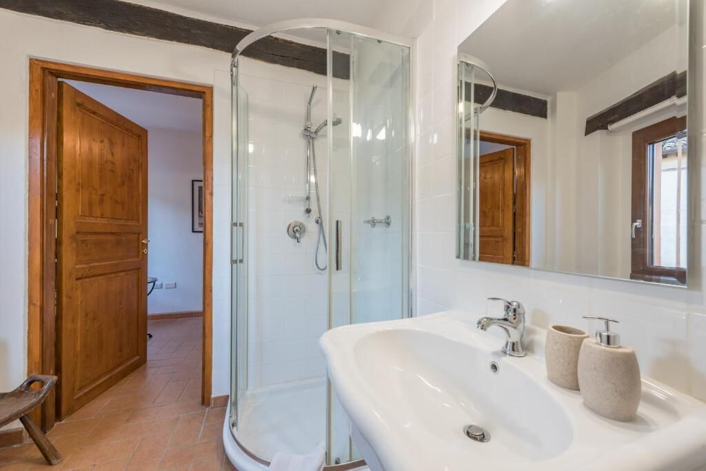 Une salle de bain moderne avec une douche à parois de verre, un grand lavabo doté de deux distributeurs de savon et un miroir au-dessus du lavabo.