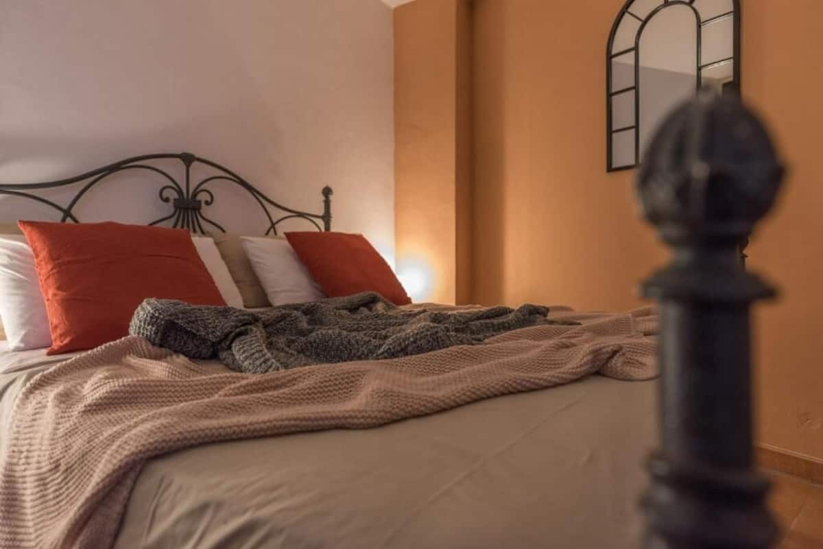 A bed with a headboard, pillows, and a blanket.