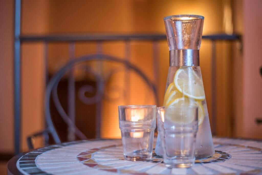 Une table sur laquelle se trouvent une carafe en verre et un verre, tous deux contenant un liquide transparent et des tranches de citron.