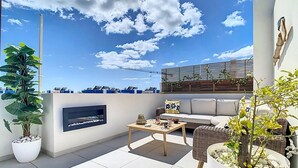A rooftop terrace with a sofa, coffee table, and potted plants. - Casa Launa Fuseta (Moncarapacho)